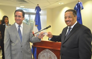 Iván Grullón recibe su nueva cédula de parte de Roberto Rosario.