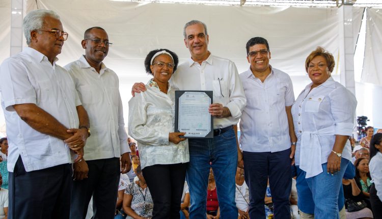 Una mujer beneficiada recibe titulo de propiedad.